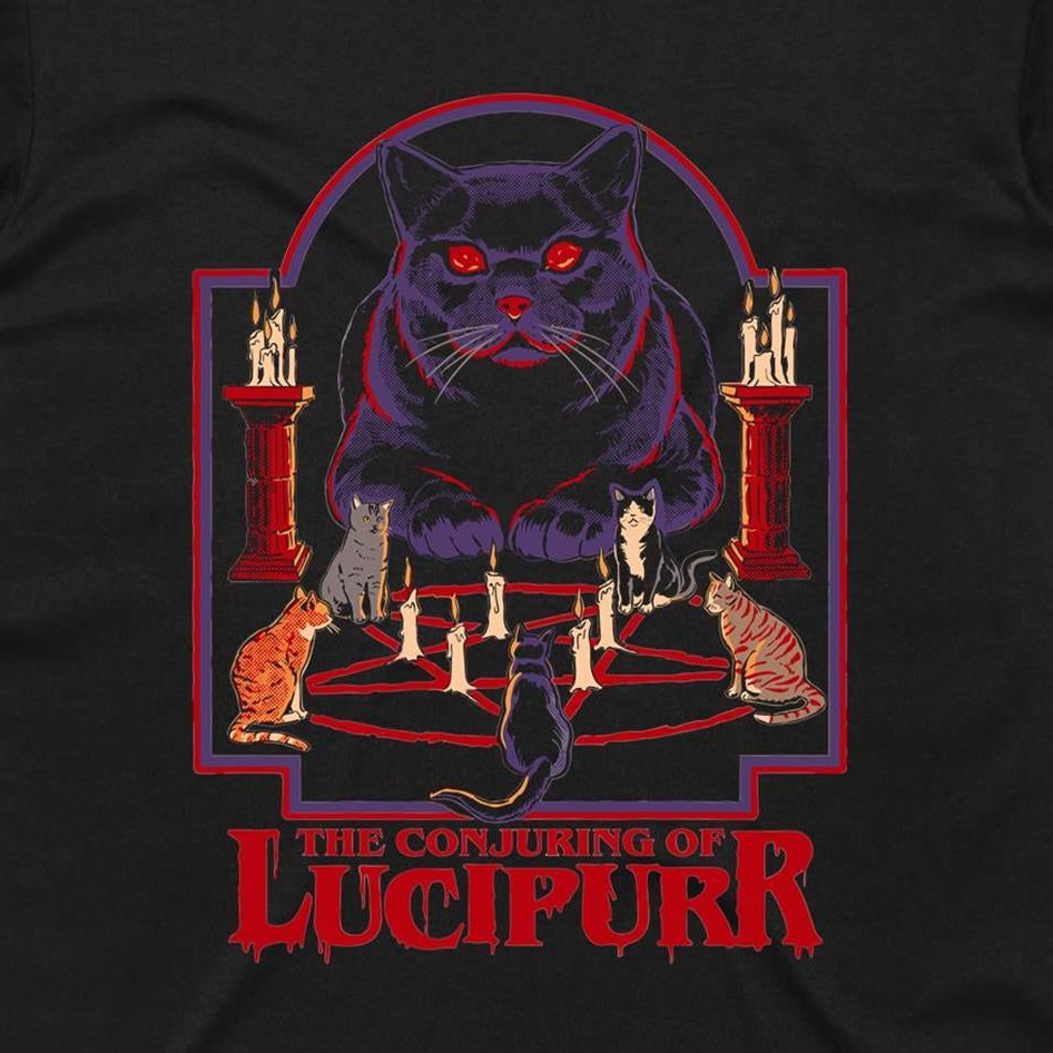A black t-shirt featuring a graphic print of 'The Conjuring of Lucipurr' from The Addams Family. The design shows a large, glowing red-eyed black cat surrounded by smaller cats on a pentagram with candles, set against a red and purple arch, with the title 'THE CONJURING OF LUCIPURR' printed in red at the bottom.