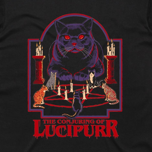A black t-shirt featuring a graphic print of 'The Conjuring of Lucipurr' from The Addams Family. The design shows a large, glowing red-eyed black cat surrounded by smaller cats on a pentagram with candles, set against a red and purple arch, with the title 'THE CONJURING OF LUCIPURR' printed in red at the bottom.