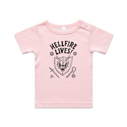A close-up of a white garment, likely a t-shirt, featuring a black graphic print. The design displays the text 'HELLFIRE LIVES!' in a distressed, arched font above a horned skull inside a shield, surrounded by fantasy icons including dice, a sword, a key, and a gem.
