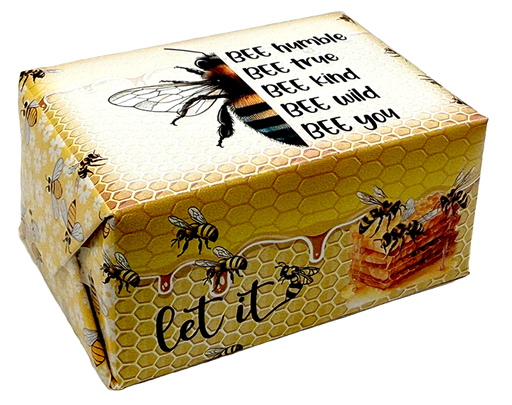 A square gift box wrapped in yellow honeycomb-patterned paper with illustrations of bees, honeycomb cells, and a honeycomb block. The top features a large bee graphic and the text 'BEE humble BEE true BEE kind BEE wild BEE you', and the bottom reads 'let it'.