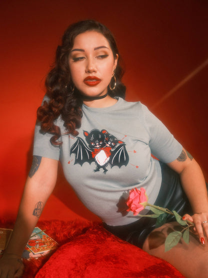 Woman wearing a t-shirt with a graphic design, sitting against a red background