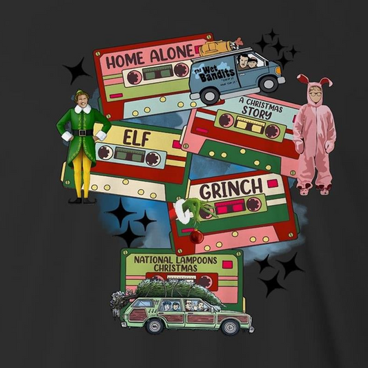 A dark gray graphic print featuring Christmas-themed cassette tapes and characters from The Grinch movie, including a green and yellow Elf, a pink Grinch in a onesie, and a green station wagon with a Christmas tree. Text includes 'Home Alone', 'Elf', 'Grinch', and 'National Lampoons Christmas'.