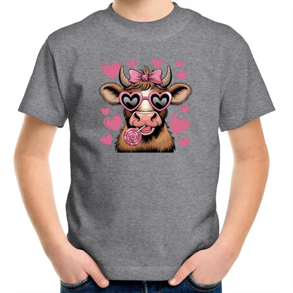 A pink youth t-shirt with a graphic print of a highland cow wearing sunglasses and licking a lollipop, surrounded by heart shapes.