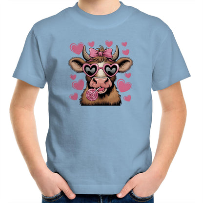 A pink youth t-shirt with a graphic print of a highland cow wearing sunglasses and licking a lollipop, surrounded by heart shapes.