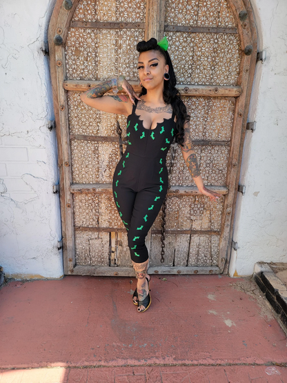 Woman in a black outfit with green patterns standing in front of an ornate wooden door.