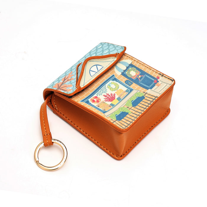 A small square leather card holder or coin purse with a tan leather exterior, a colorful illustrated patterned interior, and a gold-tone key ring, shown on a white background.