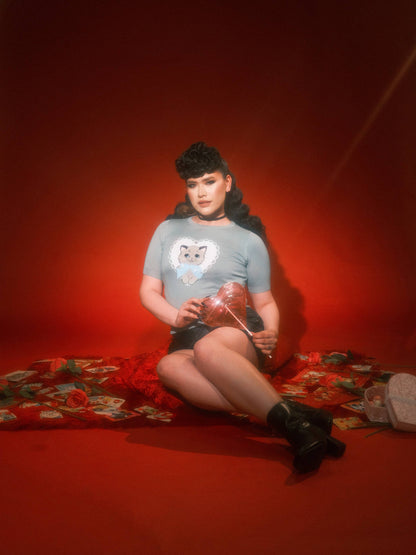 Person sitting on a red floral rug holding a clear bag with a red background