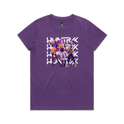 A close-up of a t-shirt featuring a graphic print of three stylized female characters in colorful outfits, overlaid with the word 'HUNTER' repeated vertically in bold white letters.