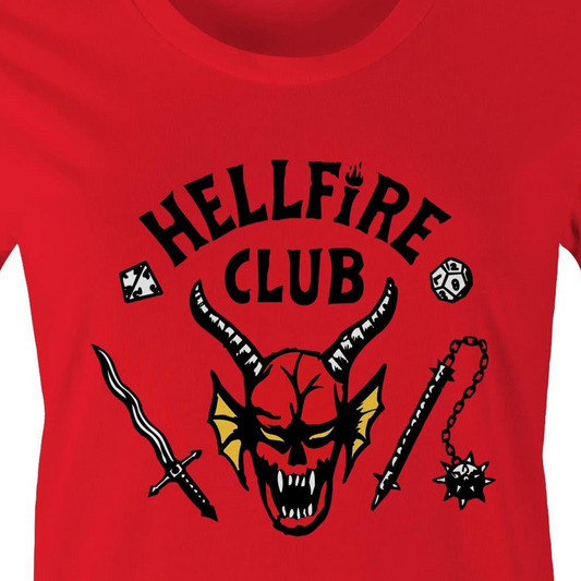A close-up of a bright red t-shirt featuring a black graphic print that reads 'HELLFIRE CLUB' above a horned devil head with yellow wings, flanked by a sword and a spiked mace.