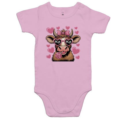 A pink baby onesie romper with a print of a cartoon cow with hearts and sunglasses on it.