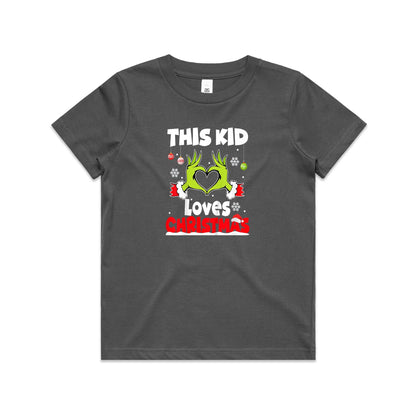 A close-up of a green Christmas t-shirt featuring a graphic of the Grinch's hands forming a heart, with the text 'THIS KID Loves CHRISTMAS' in white and red.