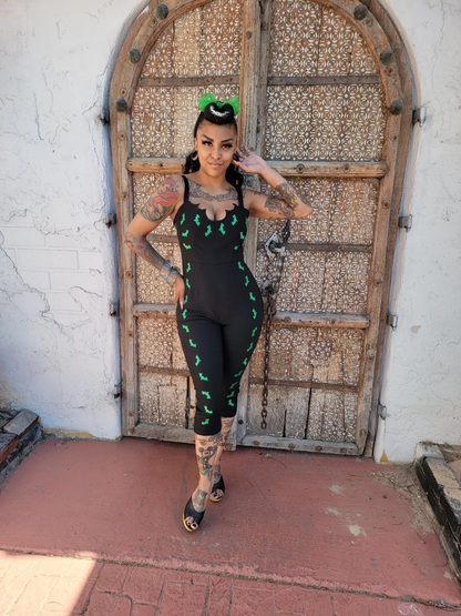 Person wearing a black outfit with green patterns in front of an ornate wooden door.