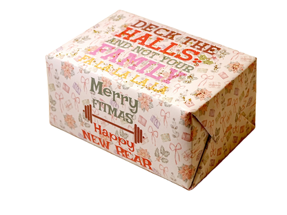 A rectangular gift box wrapped in festive holiday paper with the text 'Merry Fitsmas Happy New Bear' and 'Deck the Halls and Not Your Family Christmas Tree' printed on a light cream background with small gift and bow illustrations.