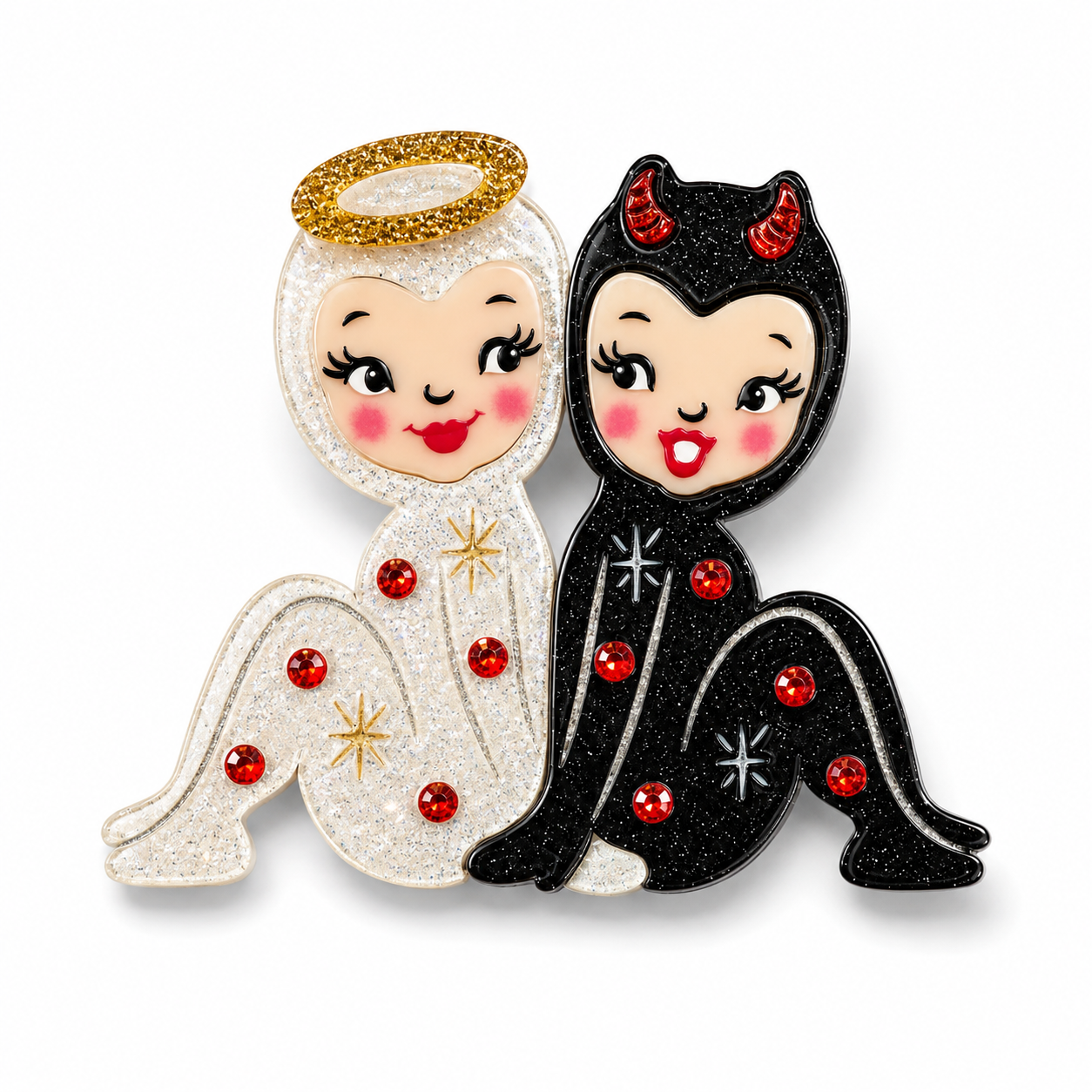 A pair of matching glittery angel and devil enamel pins side by side. The left pin depicts a white glittery angel with a gold halo, pink cheeks, and red gem accents.