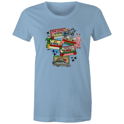 A graphic print on a light beige fabric featuring retro cassette tapes labeled 'Home Alone', 'Elf', 'The Grinch', 'National Lampoons Christmas', and 'A Christmas Story', with illustrated characters and black starbursts.