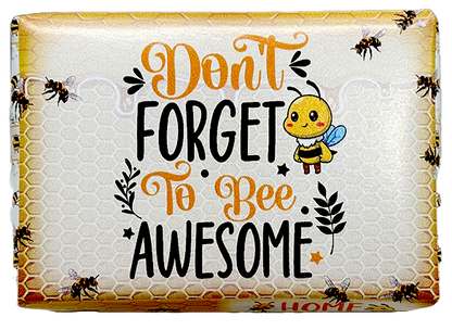 A packaged decorative item with the phrase “Don’t Forget to Bee Awesome” in orange and black lettering on a honeycomb-style background, plus a cartoon bee and bees around the border.