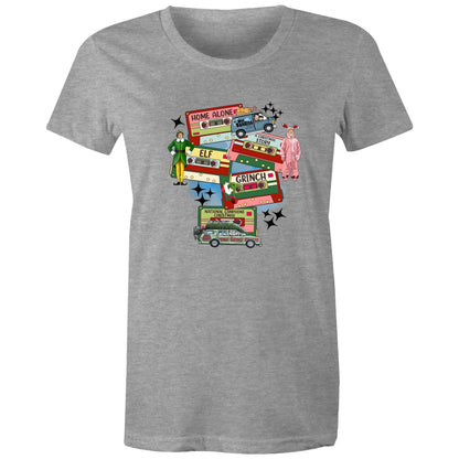A graphic print on a light beige fabric featuring retro cassette tapes labeled 'Home Alone', 'Elf', 'The Grinch', 'National Lampoons Christmas', and 'A Christmas Story', with illustrated characters and black starbursts.