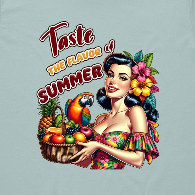 A graphic print on a light sage green t-shirt featuring a retro-style pin-up illustration of a woman with flowers in her hair, holding a basket of fresh fruit, with the text 'Taste THE FLAVOR of SUMMER' written above.