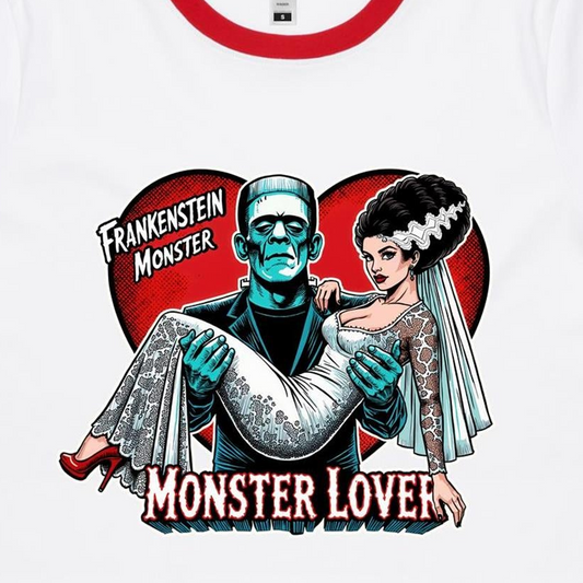 A close-up of a white crew-neck t-shirt featuring a retro Frankenstein-themed graphic print. The design shows a teal-colored Frankenstein Monster carrying a bride in a white lace wedding gown, set against a red heart background with the text 'FRANKENSTEIN MONSTER' and 'MONSTER LOVER'.