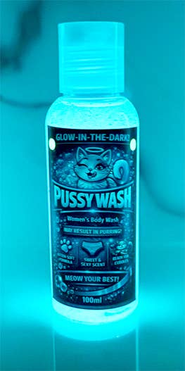 A 100ml bottle of glow-in-the-dark 'Pussy Wash' women's body wash, featuring a cartoon cat illustration on a dark label, glowing under blue light.