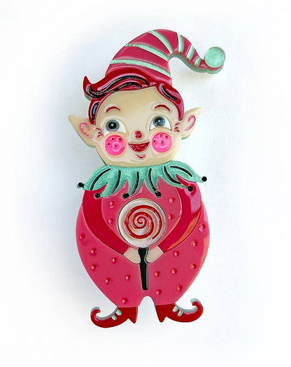 A whimsical enamel pin shaped like a strawberry with a small elf character on top, holding a lollipop. The pin features a vibrant pink strawberry body with red seeds, a green collar, and a red-and-green striped hat, set against a plain white background.