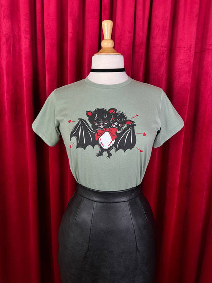 Green t-shirt with a bat graphic on a mannequin against a red curtain background