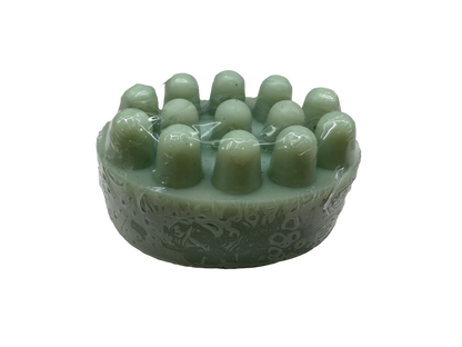 A light green jade-like circular hair massager with multiple rounded massage nodes and an engraved pattern on the side, shown on a plain white background.