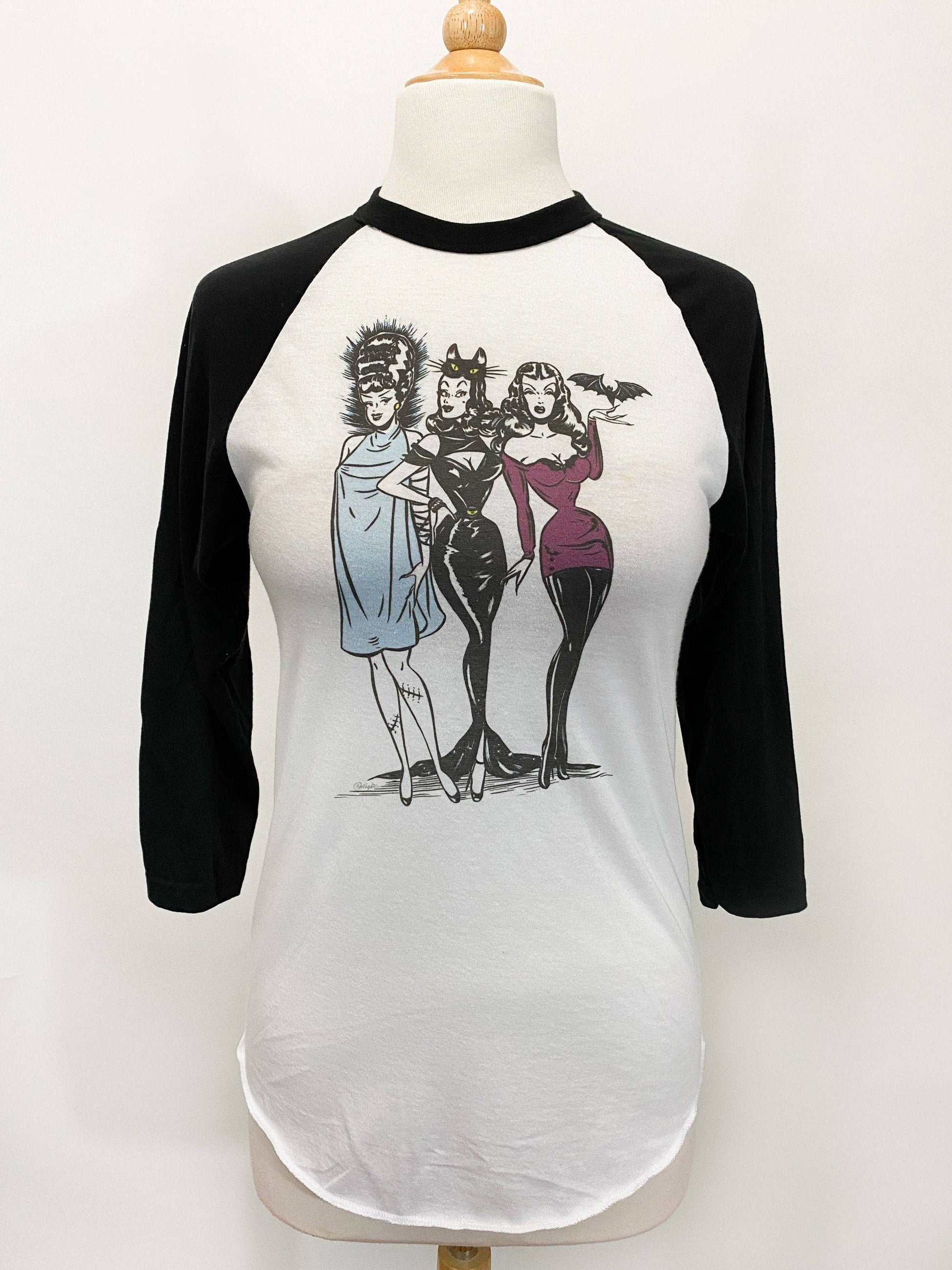 Baseball shirt with graphic of three women on a mannequin against a white background