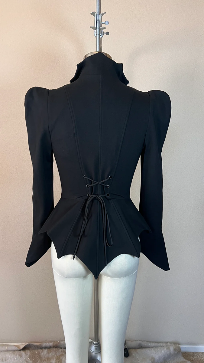 Black peplum top on a mannequin against a plain background