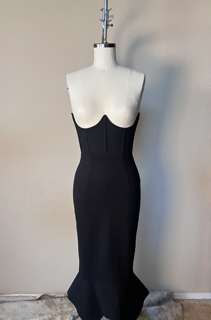 Black evening gown on a mannequin against a plain wall