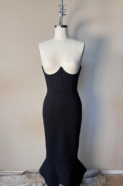 Black evening gown on a mannequin against a plain wall