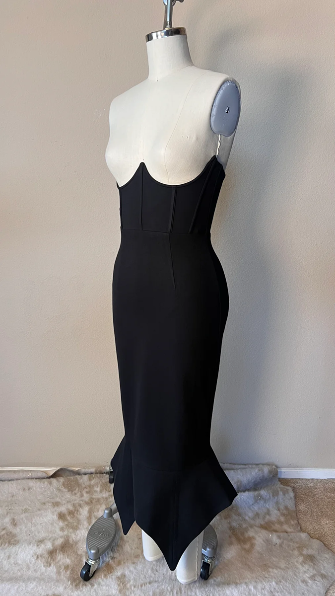 Black dress on a mannequin against a plain background