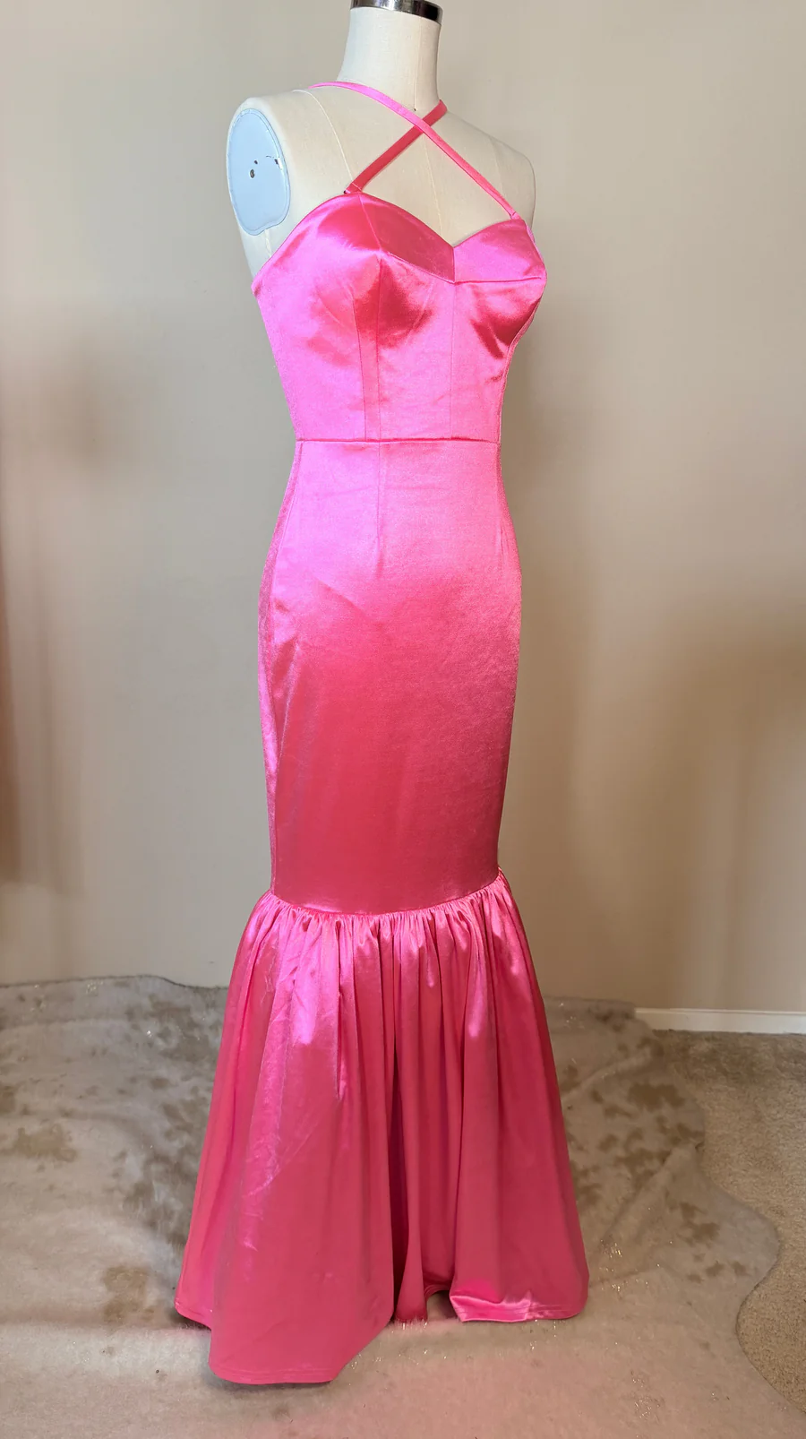Pink satin evening gown on a mannequin against a neutral background