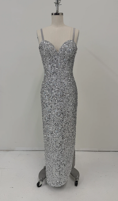 A floor-length silver sequin gown displayed on a dress form mannequin against a plain light gray wall and white floor.