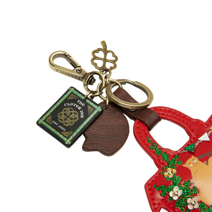 Keychain with a red bag, green book, brown leaf, and gold tag on a white background