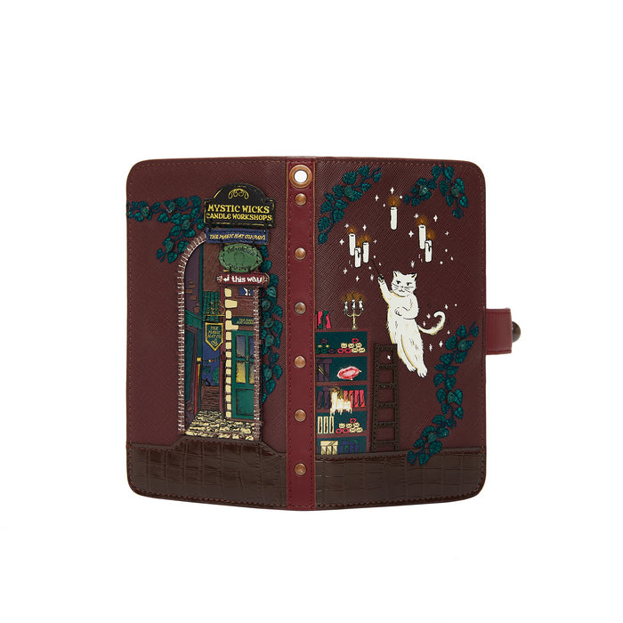 Decorative notebook with illustrations of a cat, books, and a witch's hat on a brown background.