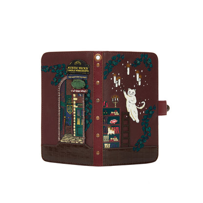 Decorative notebook with illustrations of a cat, books, and a witch's hat on a brown background.