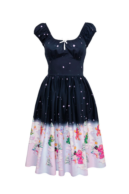 A retro-style A-line dress with a navy blue bodice fading into a light pink and white patterned hem. The bodice features a starry print, puff sleeves, and a small white bow at the neckline.