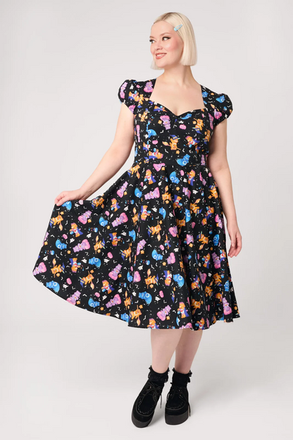 A woman modeling a black midi dress with a colorful cat print, featuring puff sleeves and a sweetheart neckline, set against a plain light gray background.