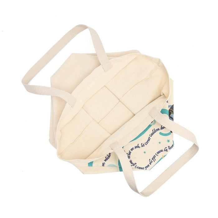 An off-white canvas tote bag with quilted paneling on the front and a printed patterned insert inside, shown on a plain white background.