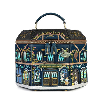 A hexagonal handbag designed to look like the 'The Corner Cabbidon' building from Harry Potter, featuring a dark navy blue base with intricate gold, green, and blue floral and architectural illustrations, topped with a dark blue handle.