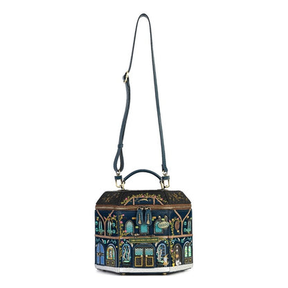 A hexagonal handbag with a dark navy blue base and an intricate multicolor architectural illustration featuring gold, green, and light blue details. It has a dark navy blue shoulder strap and top handle with gold-tone hardware, shown against a plain white background.