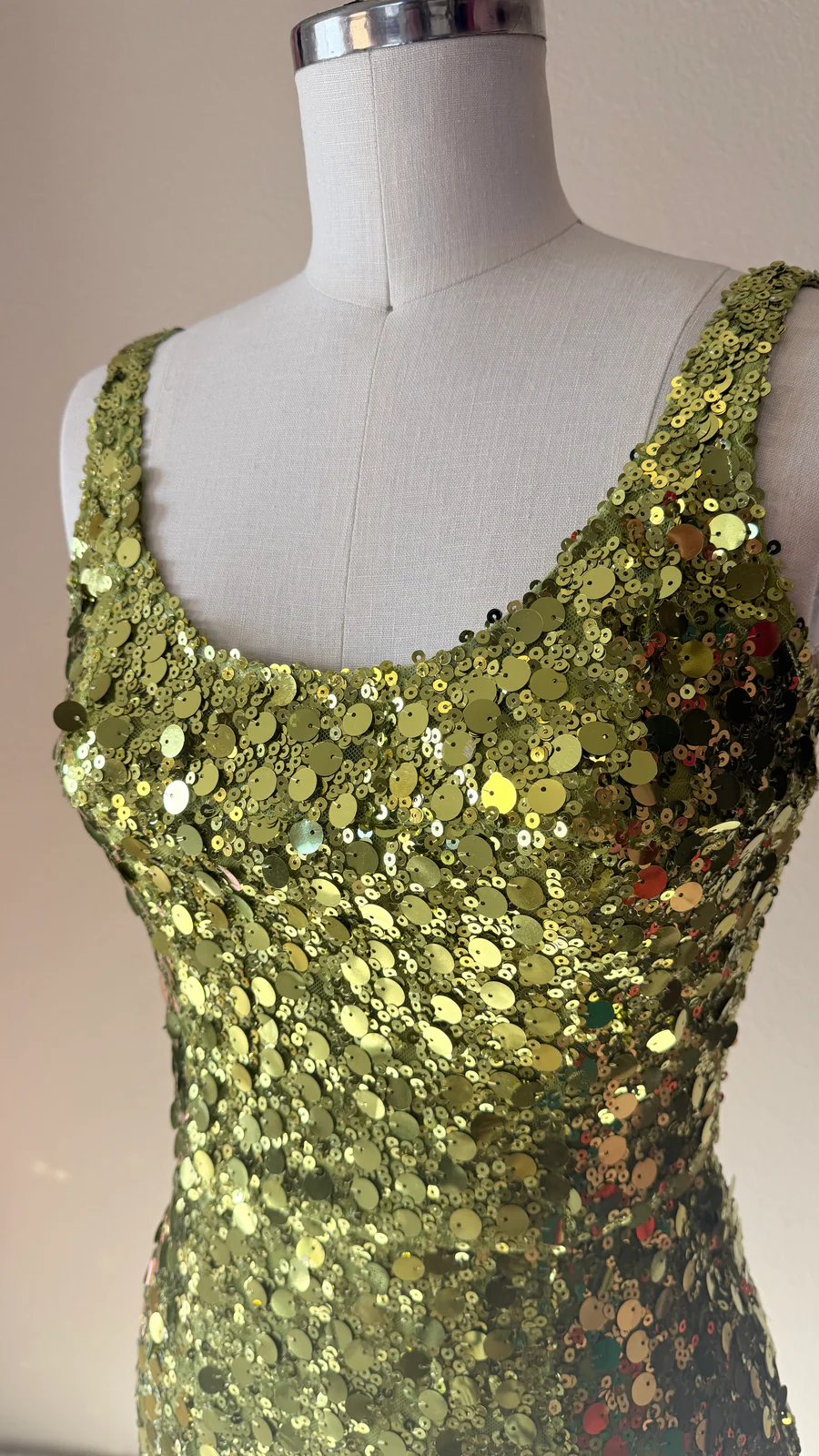Green sequin dress on a mannequin against a plain background
