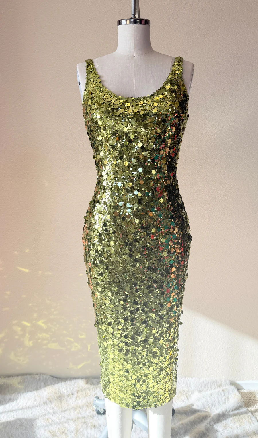 Green sequin dress on a mannequin against a neutral background