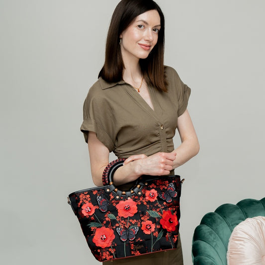 Woman holding a floral embroidered handbag against a plain background
