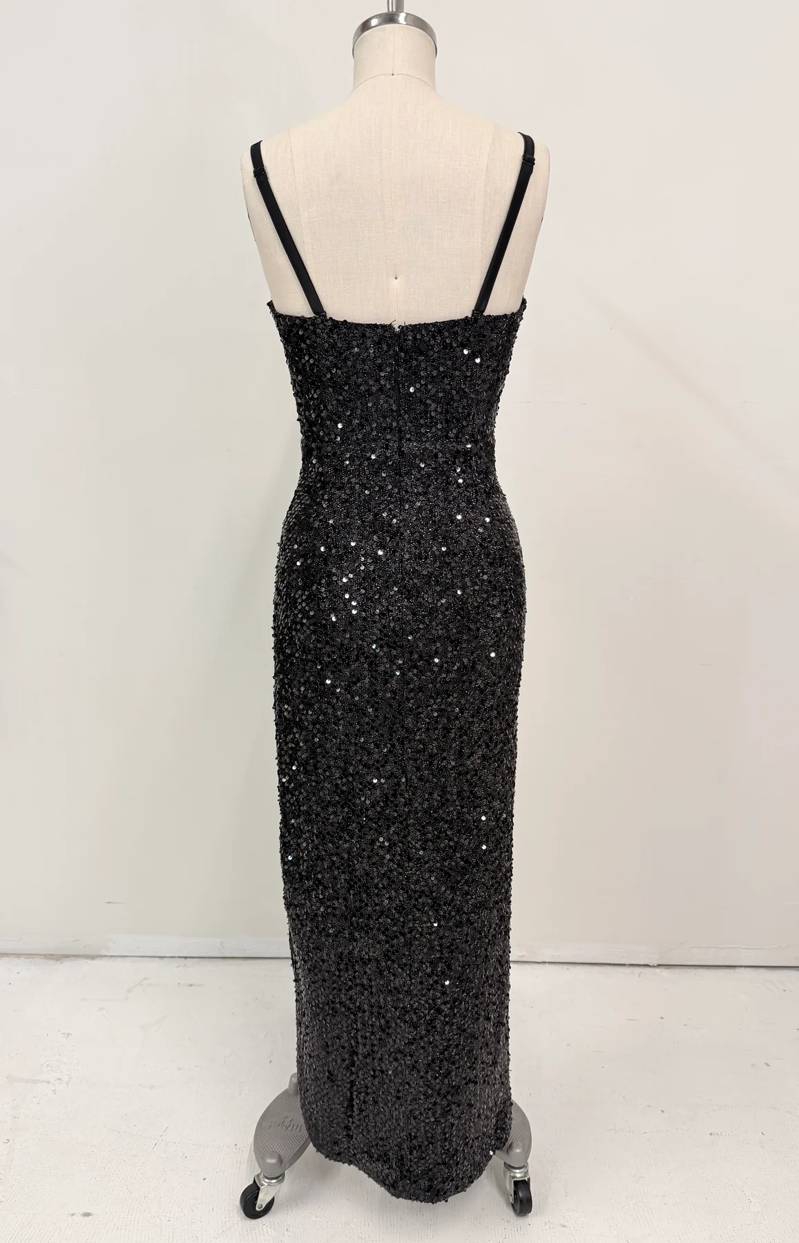 A black sequined evening gown displayed on a cream dress form mannequin against a plain white studio background.