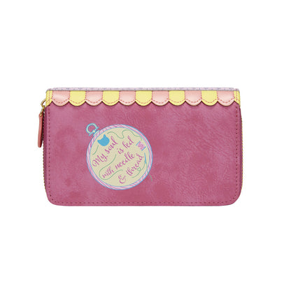 Pink wallet with decorative patch and scalloped edge on a white background