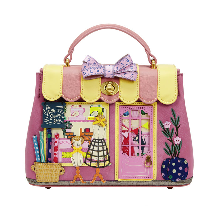 Pink handbag with colorful design and bow on a white background