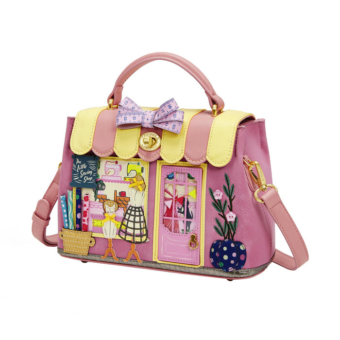 Pink handbag with colorful designs and a bow on a white background