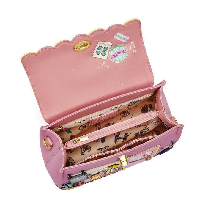 Pink handbag with a scalloped edge and interior lining featuring sewing-themed designs on a white background.